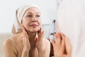 women looking in the mirror considering if she should receive Microdermabrasion treatment 