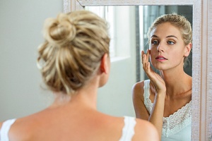 woman looking in the mirror to see results of botox in a bottle